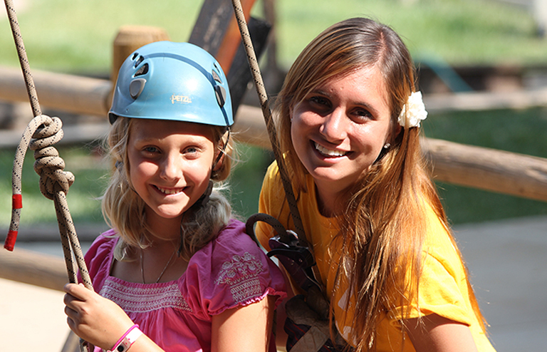 Camper with a helmet with a camp instructor.