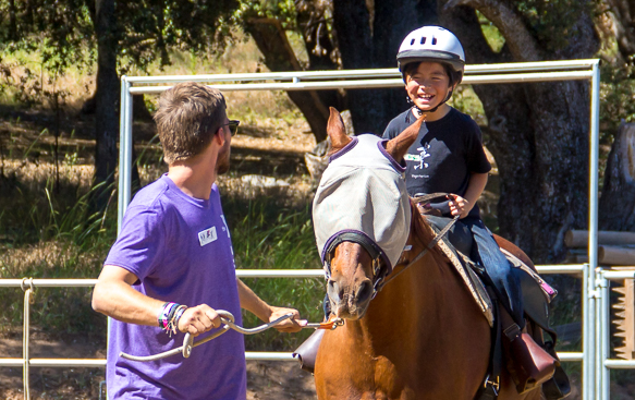 staff watching boy riding horse