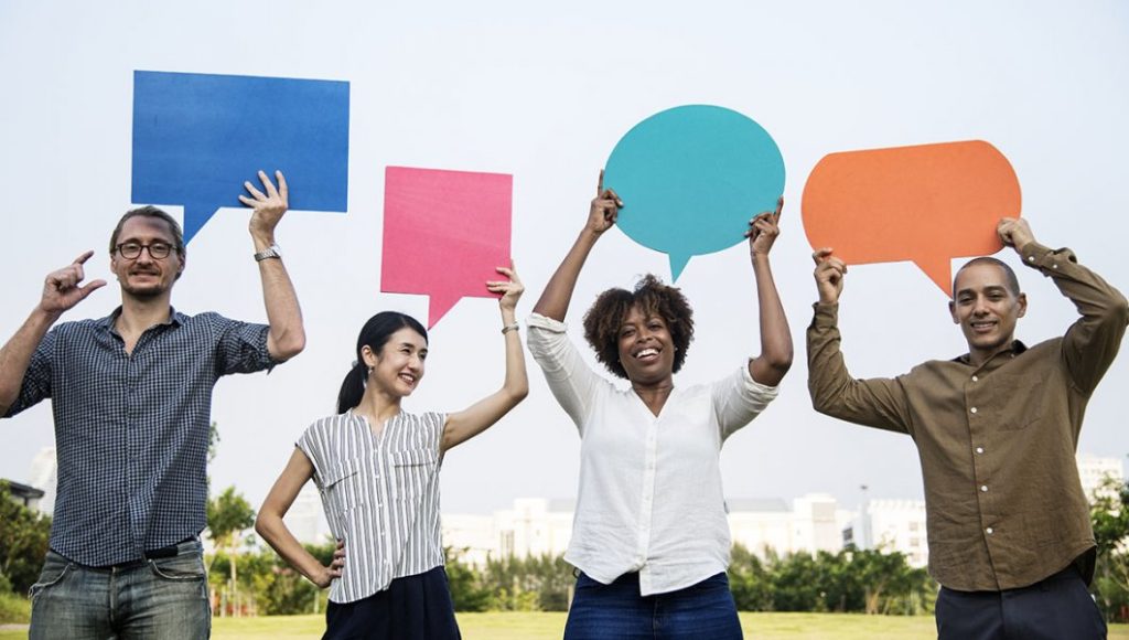 Photo of four people holding up speech bubbles