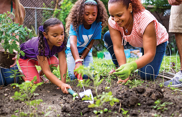 Photo of a woman volunteering to help YMCA kids with gardening