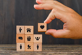 Relationship concept on wooden background side view. hand holding wooden cube with heart icon.