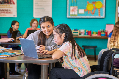 Photo of a teacher with a student on a laptop