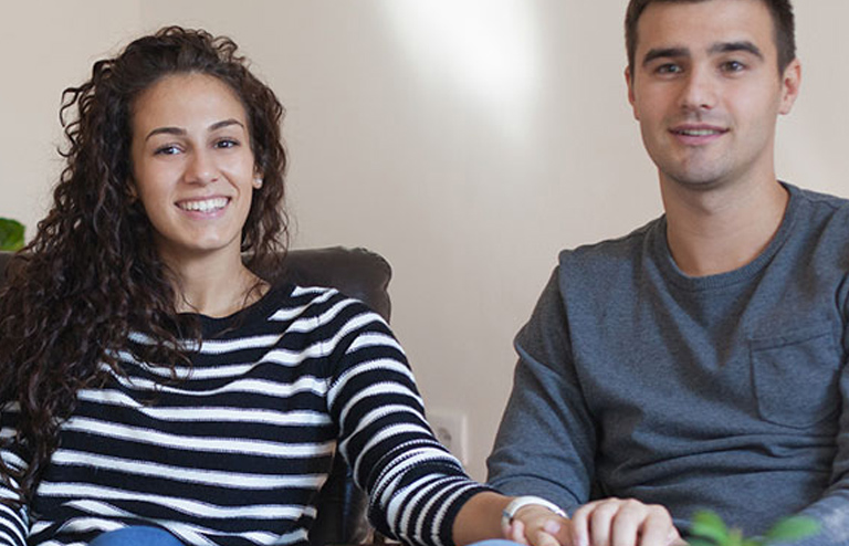 Photo of a young couple sitting together, smiling