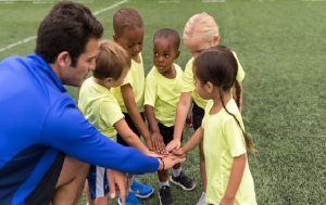 Fotografía de un entrenador con sus jugadores animando al equipo.