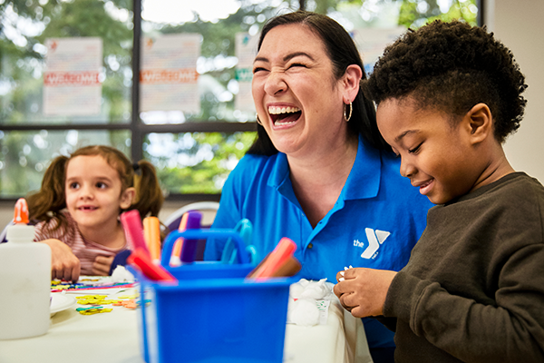 Photo of a YMCA staff member smiling with two kids