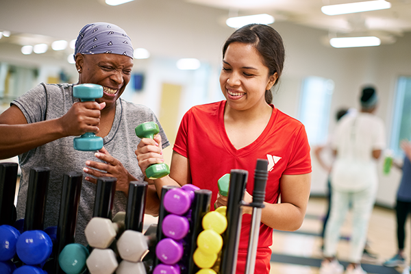 Photo of a staff member and a member trying different weights at the gym