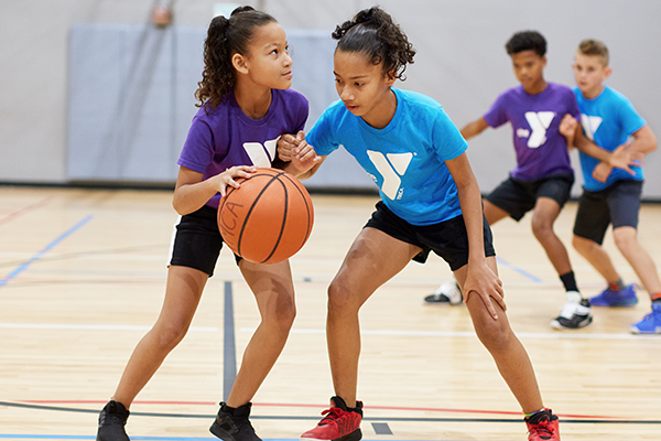 Photo of two girls playing YMCA basketball