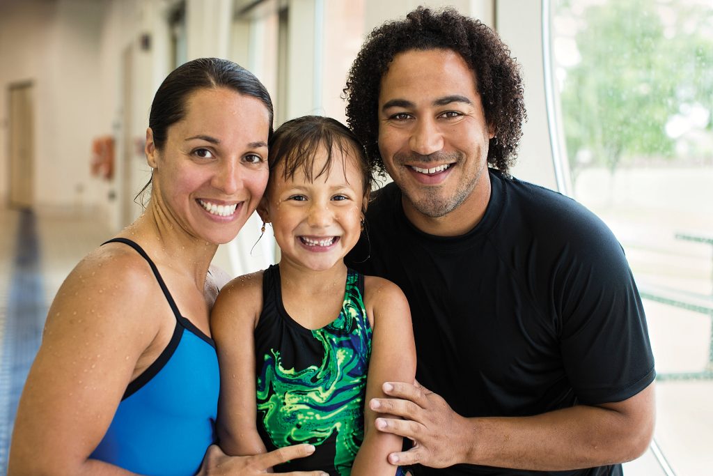 Family of three at a swimming lesson