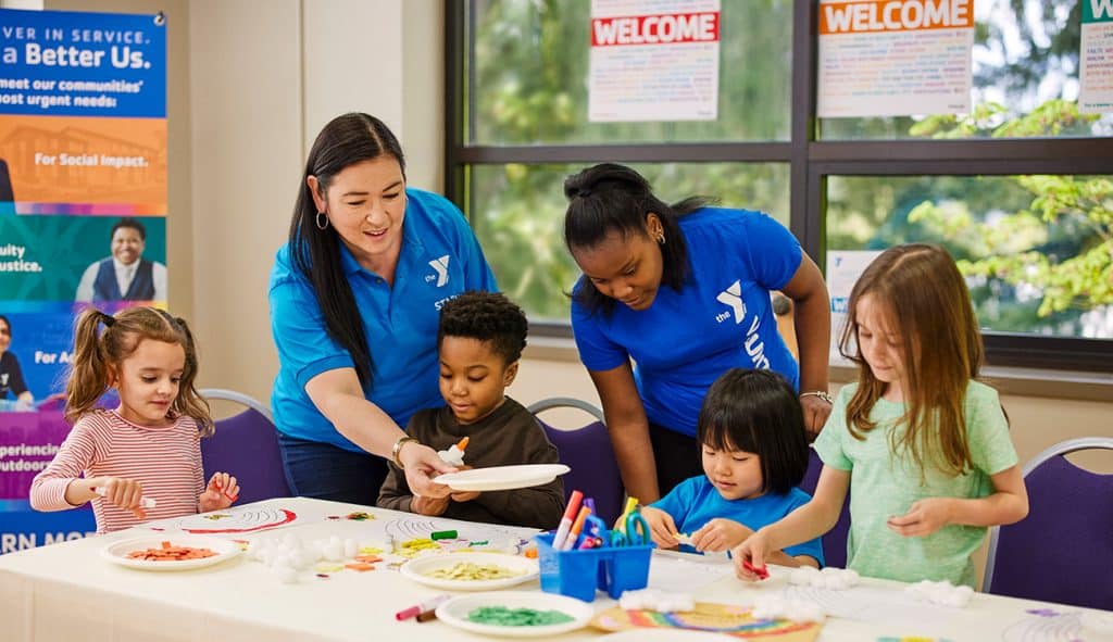 YMCA staff facilitating craft with children