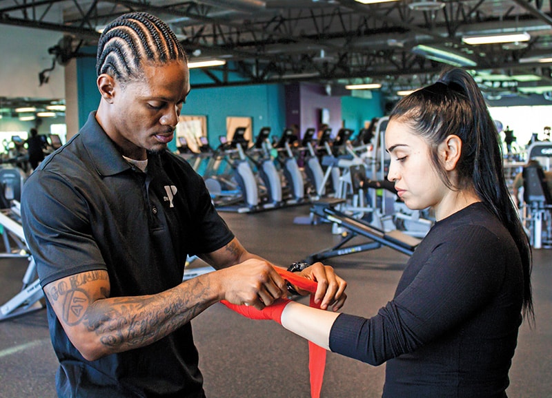 personal trainer taping hands of female client